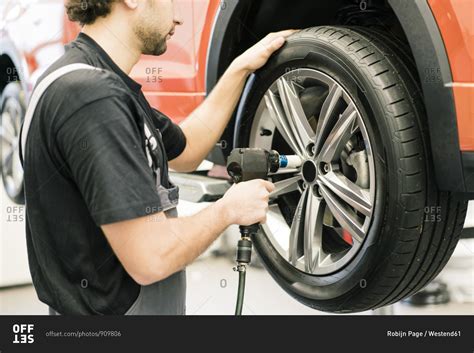 Car Mechanic In A Workshop Changing Tire Stock Photo Offset