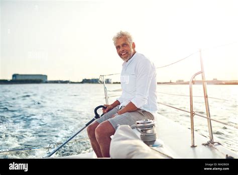 Smiling Mature Man Sitting On The Deck Of His Boat Enjoying A Sunny Day