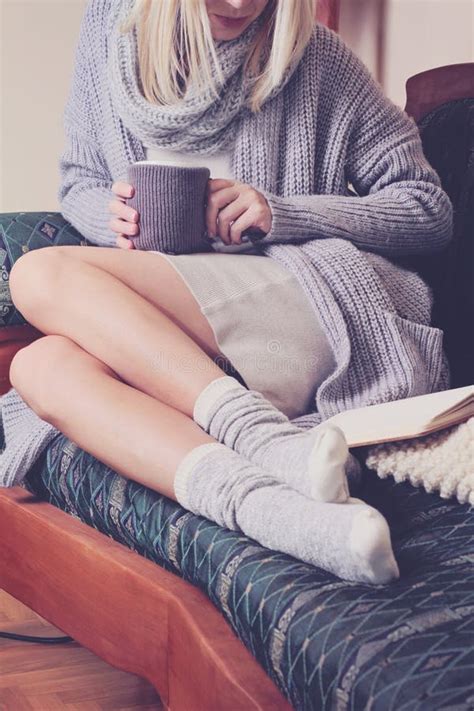 Beautiful Woman Wearing Cozy Sweater And Warm Wool Socks Reading A Book Sitting On Comfortable