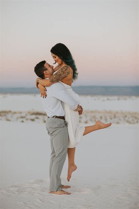 a man holding a woman in his arms on the beach