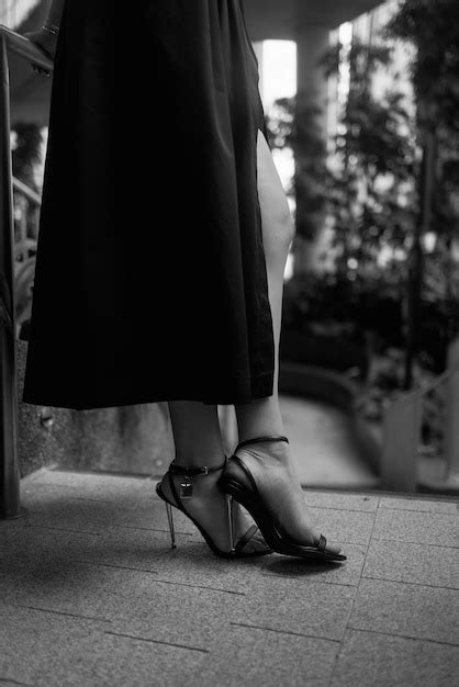 Premium Photo A Woman In A Black Dress Stands On A Sidewalk In Front