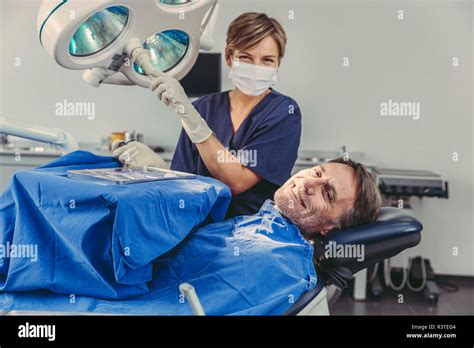 Patient Smiling At Dental Surgeon After Successful Treatment Stock