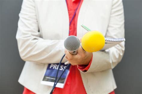 Female Journalist At News Conference Writing Notes Holding Microphone
