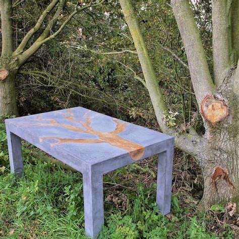 a blue table sitting next to a tree in the grass near some leaves and branches