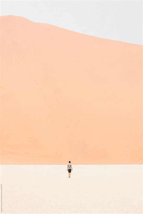 View Of A Young Man Walking In The Middle Of The Desert With A Big