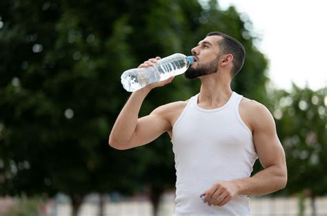 Premium Photo Sporty Young Man Drinking Water In Park