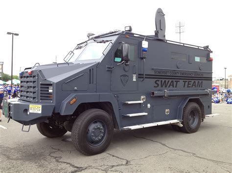 An Armored Swat Team Vehicle Parked In A Parking Lot With People