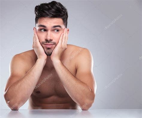 Hombre desnudo con la cabeza en las palmas mirando a un lado fotografía de stock feedough