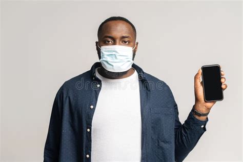 African American Man Wearing Medical Mask Shows Smartphone With An