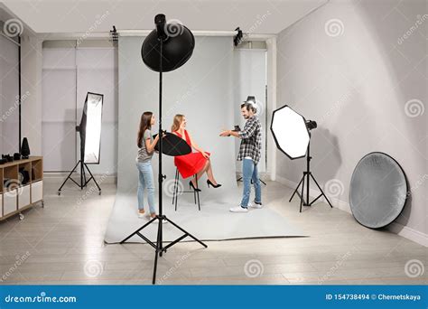 Professional Photographer With Assistant Taking Picture Of Young Woman