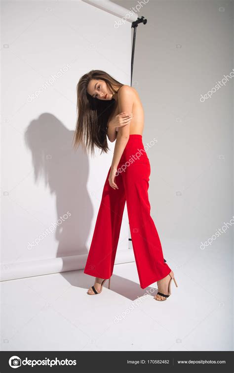 Beautiful Naked Woman In Red Pants Posing Casting Shadow Isolated On The Gray Background Stock