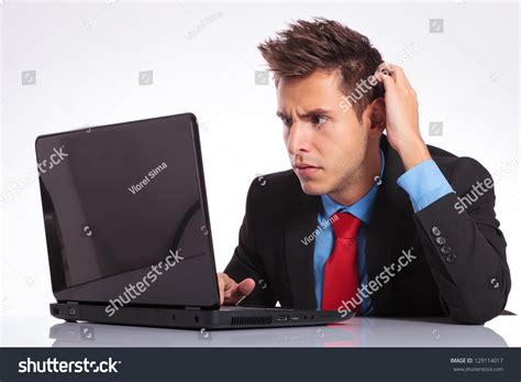 Young Business Man Sitting At The Desk And Looking Baffled At His