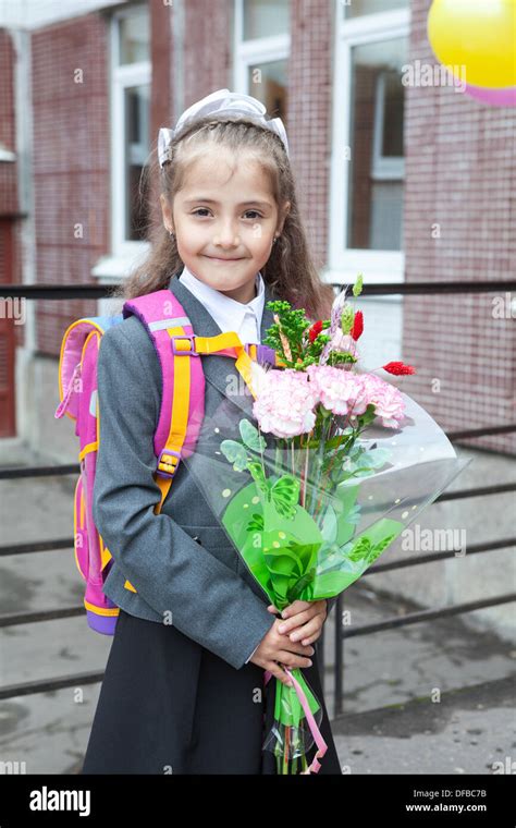 Russian Schoolgirl With Flowers In Hands And Schoolbag On The Back