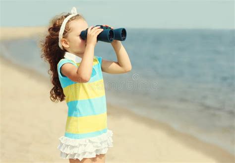 Portrait Little Girl Child Looking Through Binoculars On A Sea Beach
