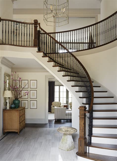 Example of a small transitional light wood floor and beige floor entryway design in minneapolis with gray walls and a black front door another chest with round mirror. Grand curved stairway design in entryway | Amy Meier ...