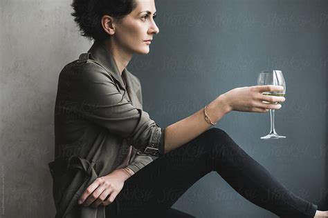 short dark haired woman with a glass of white wine del colaborador de stocksy irina efremova
