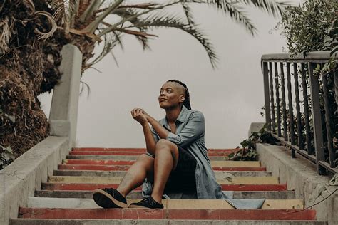 Woman Looking Up Toward Sky While Sitting On Colorful Stairs By