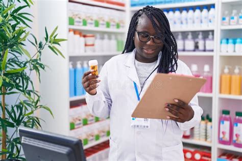 African American Woman Pharmacist Holding Pills Bottle Reading Document