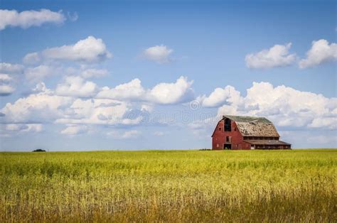 Old Red Barn Sitting In A Field In The Distance Under A Blue Sky With