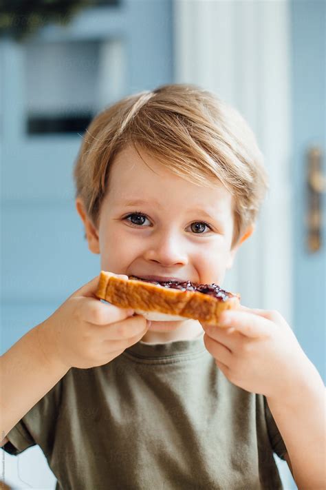 Young Boy Eating Toast With Jam For Breakfast By Stocksy Contributor