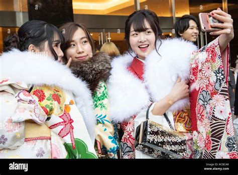 japanese girls dressed in colorful kimonos pose for a selfie during the coming of age day