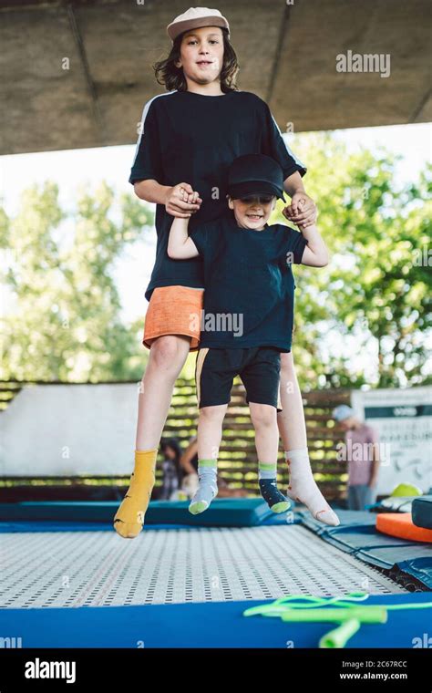 Two Little Boys Jumping On Trampoline In Sport Center Kids Having Fun