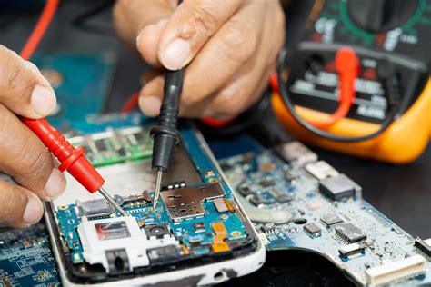 Technician Repairing Inside Of Mobile Phone By Soldering Iron