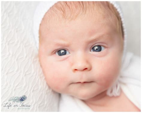 Close Up Portrait Photo Newborn Baby With Eyes Open In White Bonnet