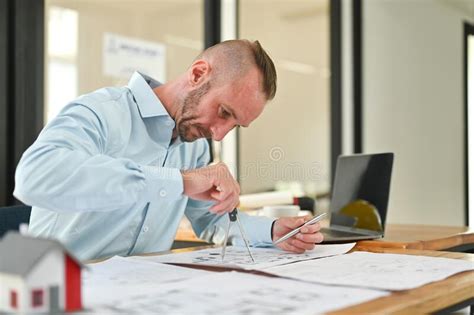 Concentred Caucasian Architect Man Working With Blueprint Sketching A