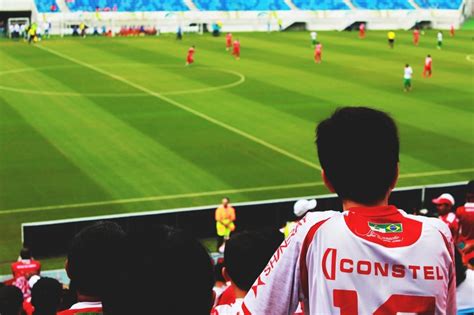 Boy In White And Red Constel Jersey In Audience Stand Watching Soccer