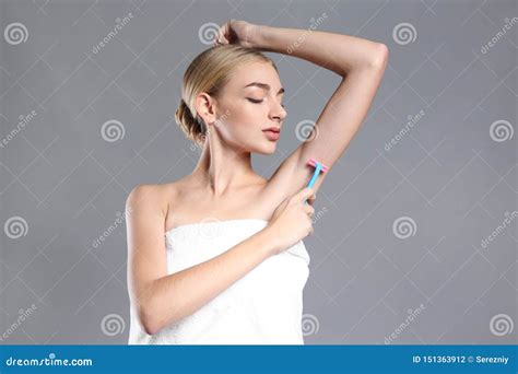 Beautiful Young Woman Shaving Armpits On Grey Background Stock Photo