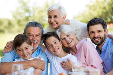 Familia Que Se Sienta En La Tabla Al Aire Libre Sonriendo Imagen De