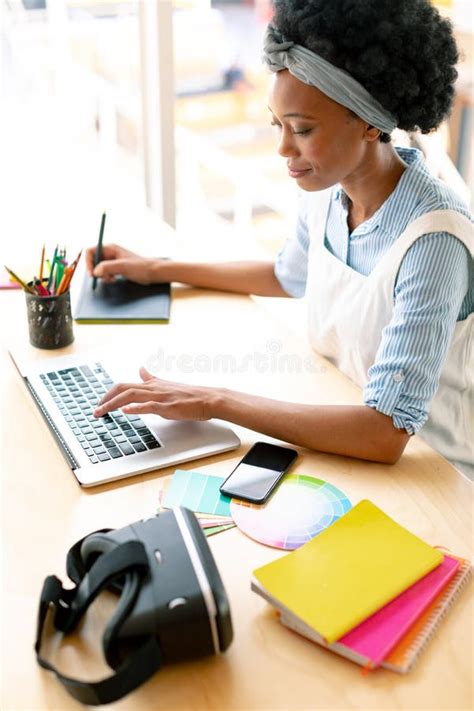 Female Graphic Designer Using Graphic Tablet And Laptop At Desk Stock