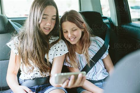 Two Teenage Girls Looking At A Phone In A Car By Stocksy Contributor