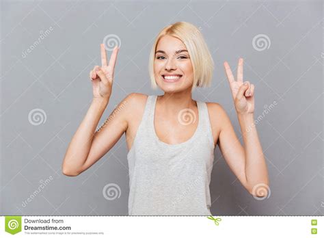 Cheerful Cute Young Woman Showing Peace Sign With Both Hands Stock