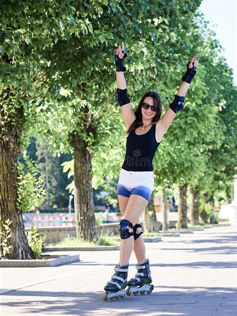 Young Pretty Brunette Woman Riding Roller Blades In City Park In The