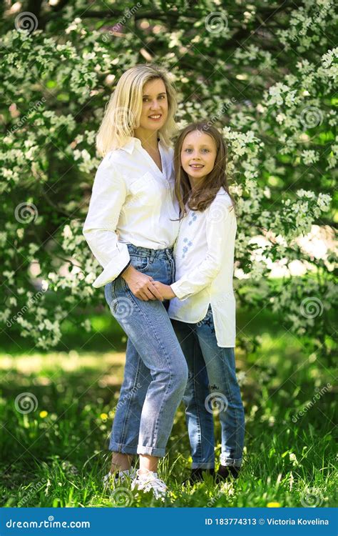 Mother And Daughter In The Blooming Rose Gardens Of Apple Trees Happy