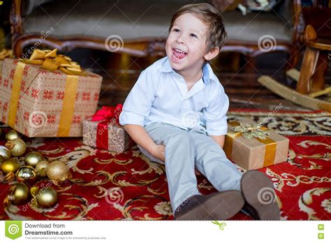 Young Boy Sitting On The Carpet With Christmas Ts Stock Image