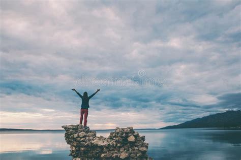 The Girl Stands On A Pile Of Stones And Looks At The Sea Stock Photo