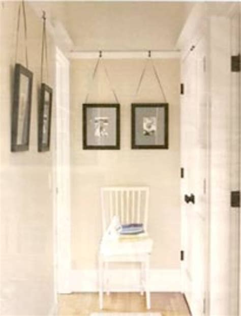 a white chair sitting in a hallway next to two pictures on the wall and a door