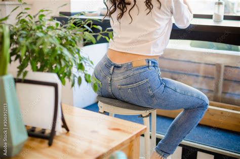 Stylish Girl In A White T Shirt And Jeans Sits In A Cafe On The Bar Stool Beautiful Ass Of A