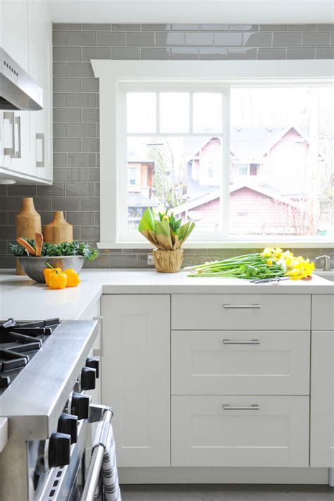 The warm, dark gray tones of the countertops keep the monochromatic. White Kitchen with Grey Backsplash - Transitional - Kitchen