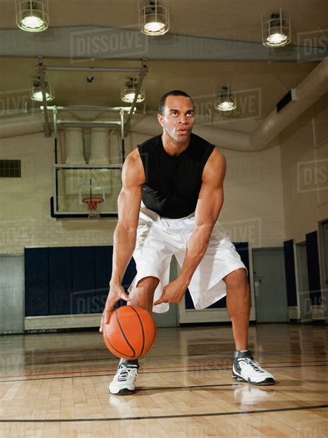 Mixed Race Man Playing Basketball On Basketball Court Stock Photo