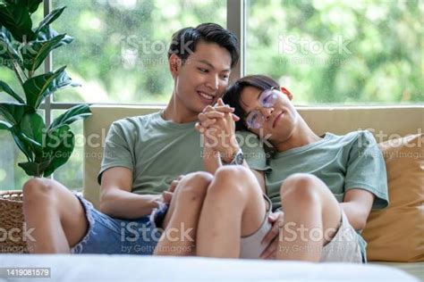 Happy Asian Gay Couple Holding Hands Together Relaxing At Home On Sofa