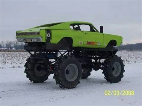 A Green Monster Truck With Large Tires In The Snow