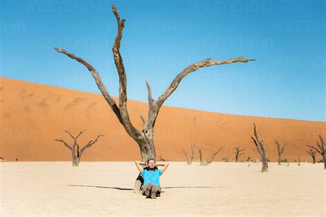 Namibia Namib Desert Man Resting At Dead Tree In Deadvlei Stock Photo