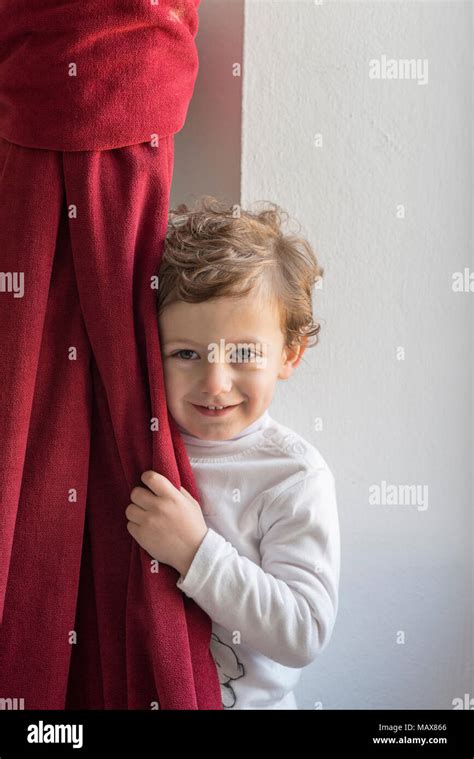 Child Hiding Behind A Red Curtain With Smiling Gesture Stock Photo Alamy