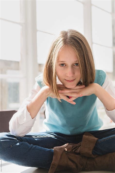 Tween Girl Sitting Cross Legged On Table Looking At Camera By