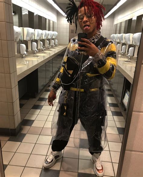 A Man With Dreadlocks Standing In A Bathroom Looking At His Cell Phone