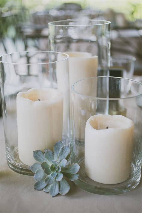 A Trio Of Led Pillar Candles In Vases With Pale Green Succulents Tucked